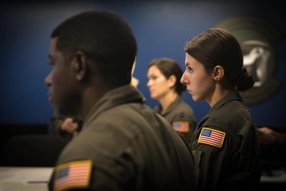 Combat Camera Airman listening to flight briefing